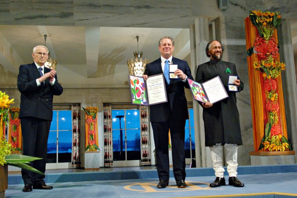 Two men showing their medals and diplomas while another man is applauding