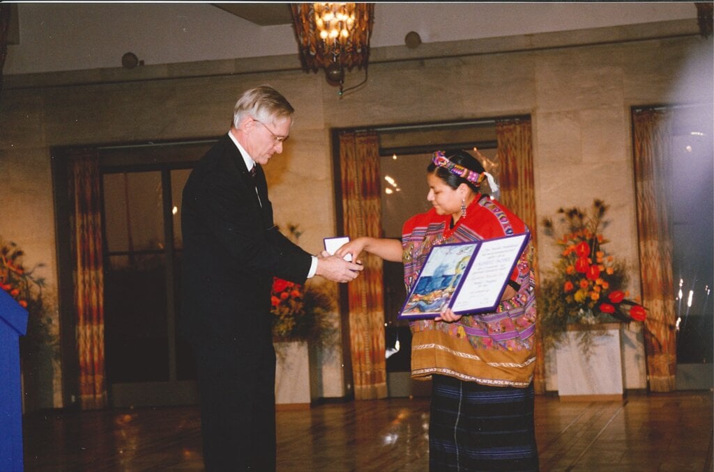 A woman is presented a medal and a diploma from a man during a ceremony