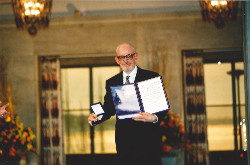 A man showing a medal and a diploma