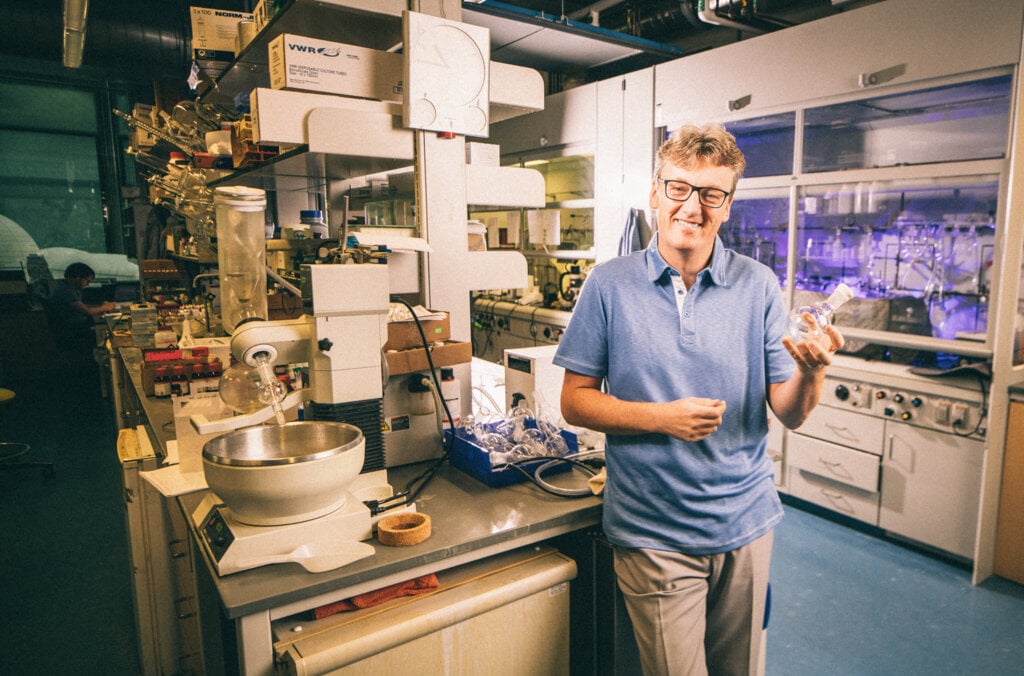 David MacMillan stands smiling in a science laboratory.