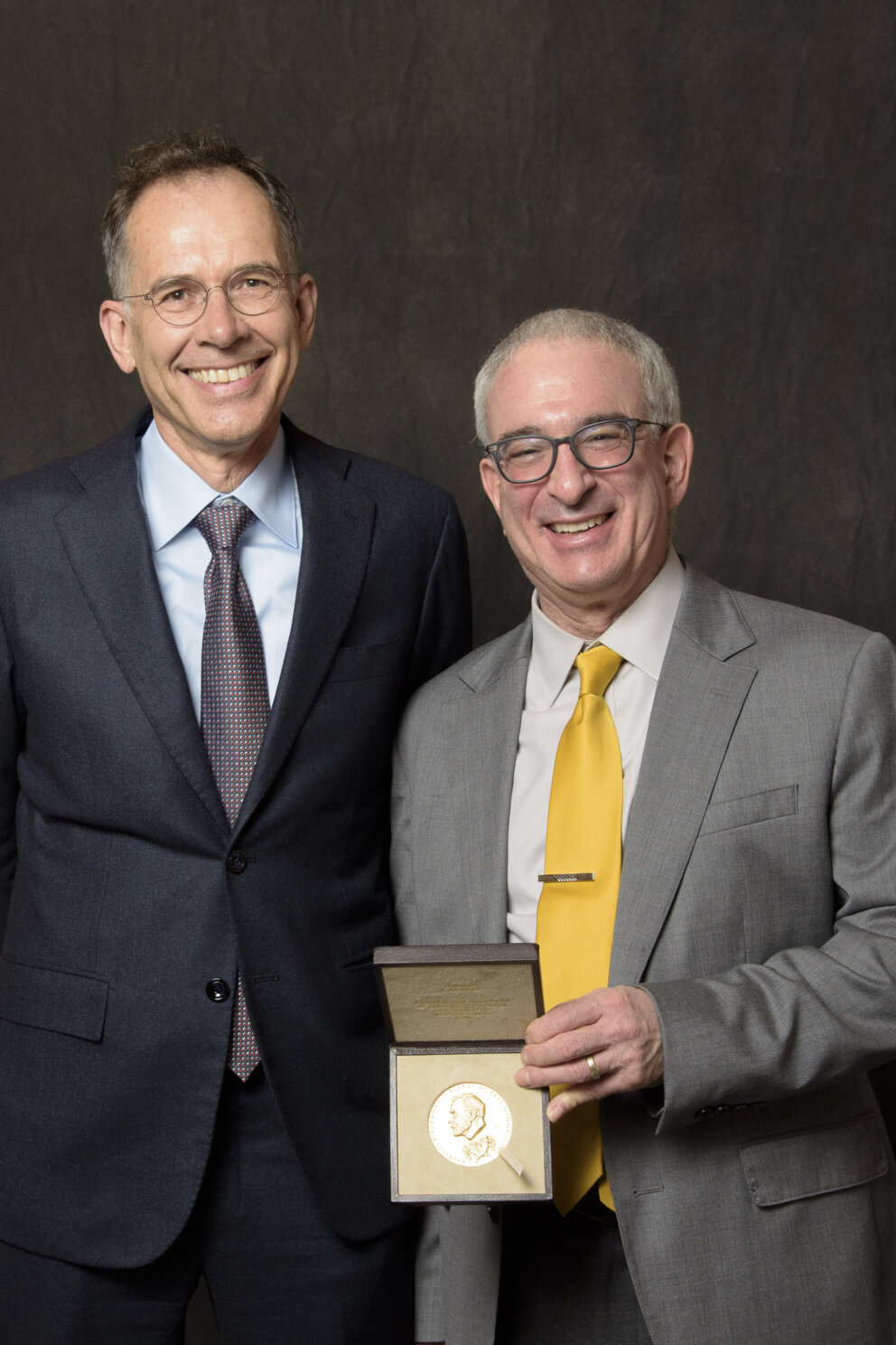 Guido Imbens and Joshua Angrist pose for a formal photo with Angrist's economic sciences prize medal