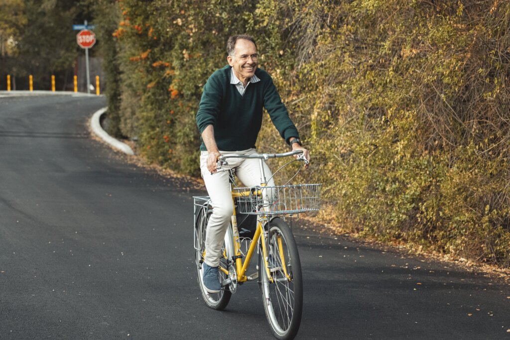 Economic science laureate Guido Imbens riding a yellow bike on a leafy road