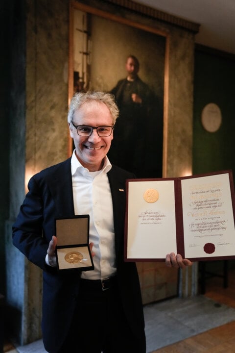 A man showing a diploma and a medal