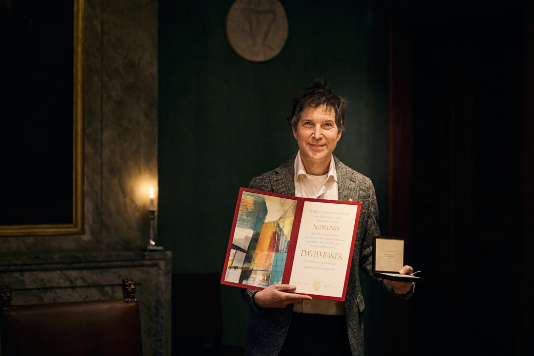 A man showing a diploma and a medal