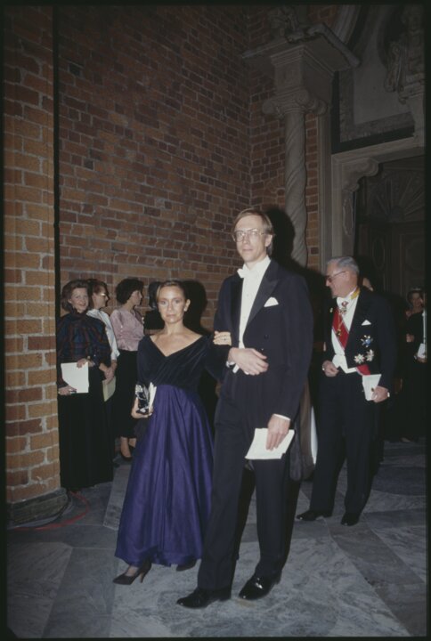 A man and a woman proceed through a hall