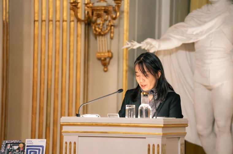 A woman in a lectern in a beautiful hall