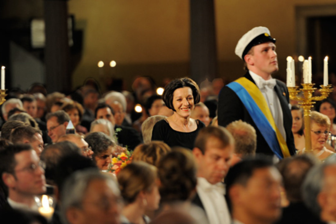 Escorted by a student, Herta Müller walks towards the podium to deliver her Banquet speech