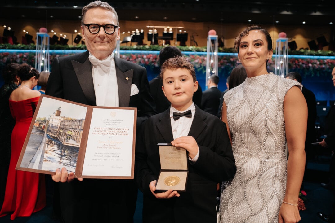 A man showing a diploma, beside him a boy is showing a medal. A woman is standing beside them