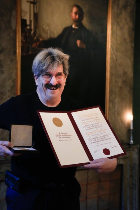 A man showing a diploma and a medal