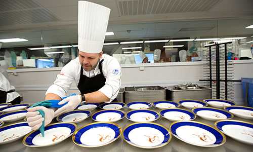 In the kitchen, the chefs prepare a three course dinner for the about 1,250 guest