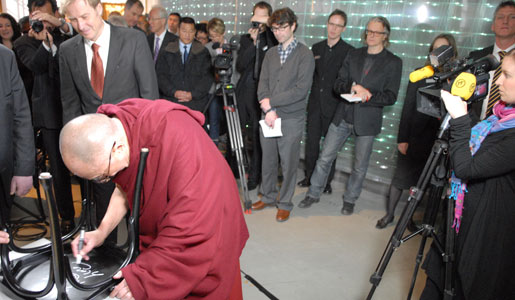 The Dalai Lama autographs a chair