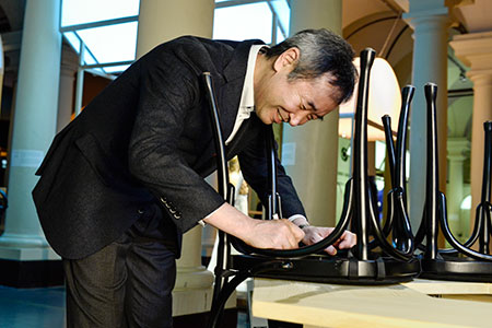Like many Nobel Laureates before him, Takaaki Kajita autographs a chair at Bistro Nobel at the Nobel Museum in Stockholm.