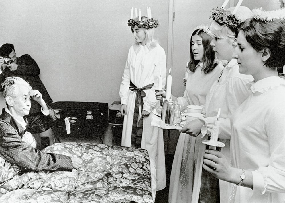 A man in a bed is greeted by the Lucia
